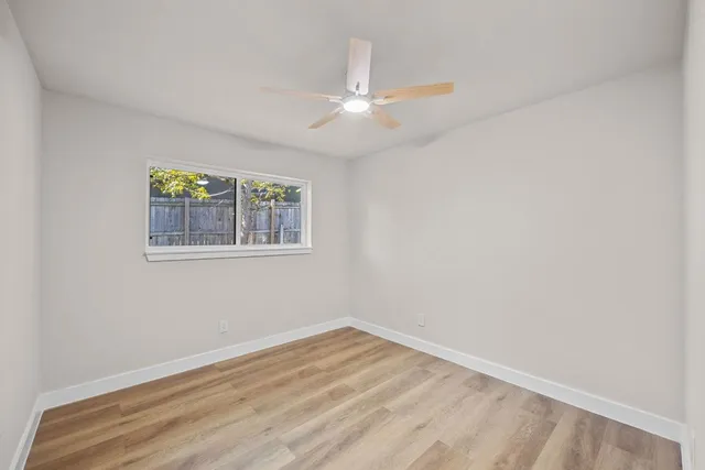 an empty room with a window and a fan
