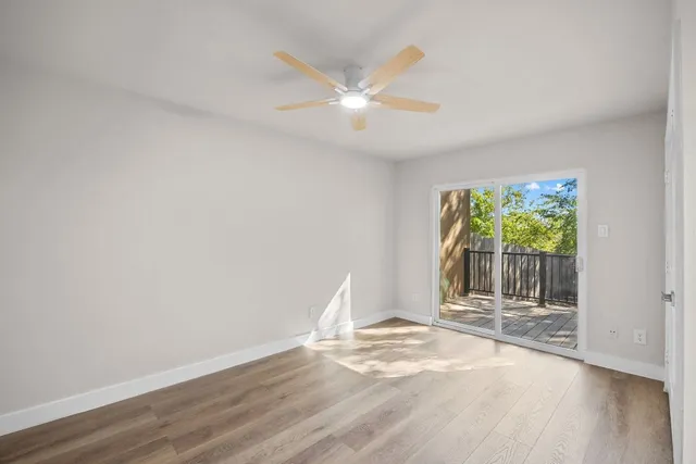 a view of empty room with wooden floor and ceiling fan