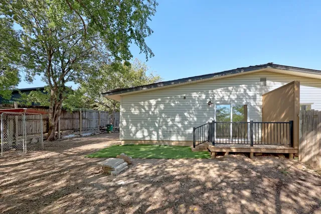 a view of a backyard with large trees and wooden fence