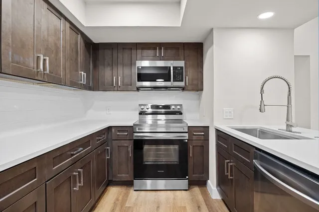 a kitchen with stainless steel appliances granite countertop a stove a sink and a microwave