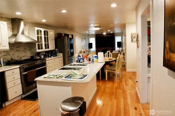 a kitchen with stainless steel appliances granite countertop a stove a sink a refrigerator and a dining table