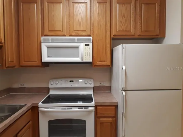 a kitchen with appliances a refrigerator and cabinets