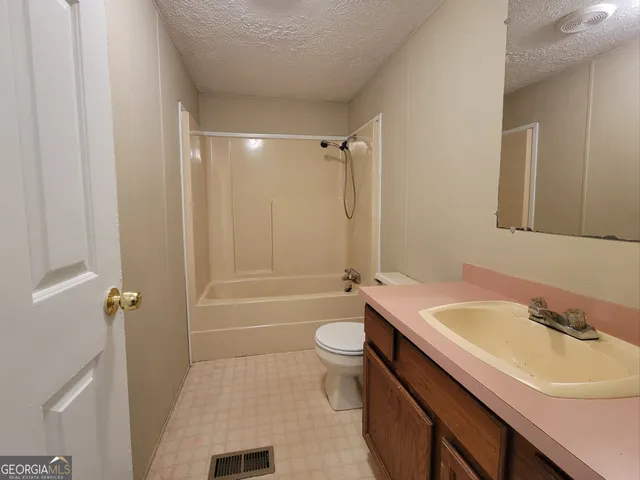 a bathroom with a sink a toilet a tub and shower