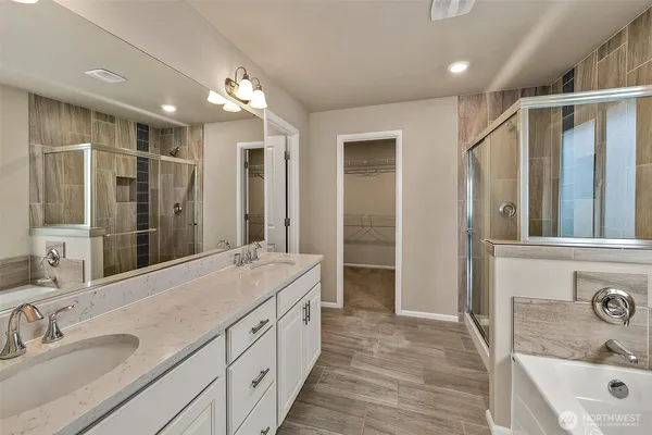 a bathroom with a sink double vanity granite tub shower and a mirror