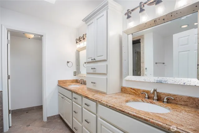 a bathroom with a granite countertop double vanity sink and a mirror