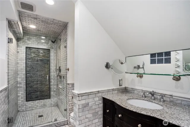 a bathroom with a granite countertop sink a mirror and shower