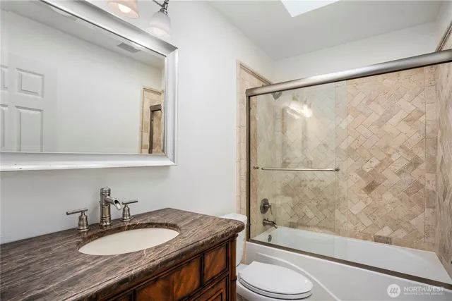 a bathroom with a granite countertop sink toilet a mirror and shower