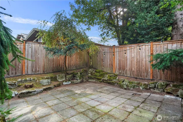 a backyard of a house with plants and trees with wooden fence