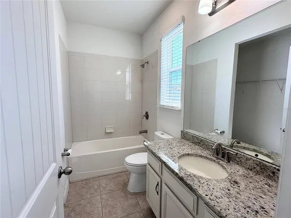 a bathroom with a granite countertop sink a toilet and bathtub