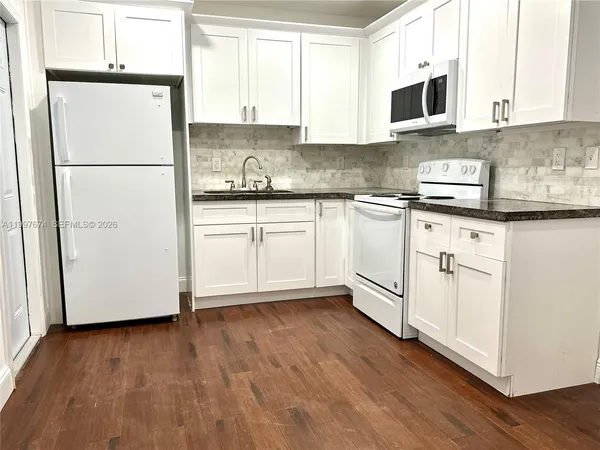a kitchen with stainless steel appliances granite countertop a refrigerator sink and white cabinets