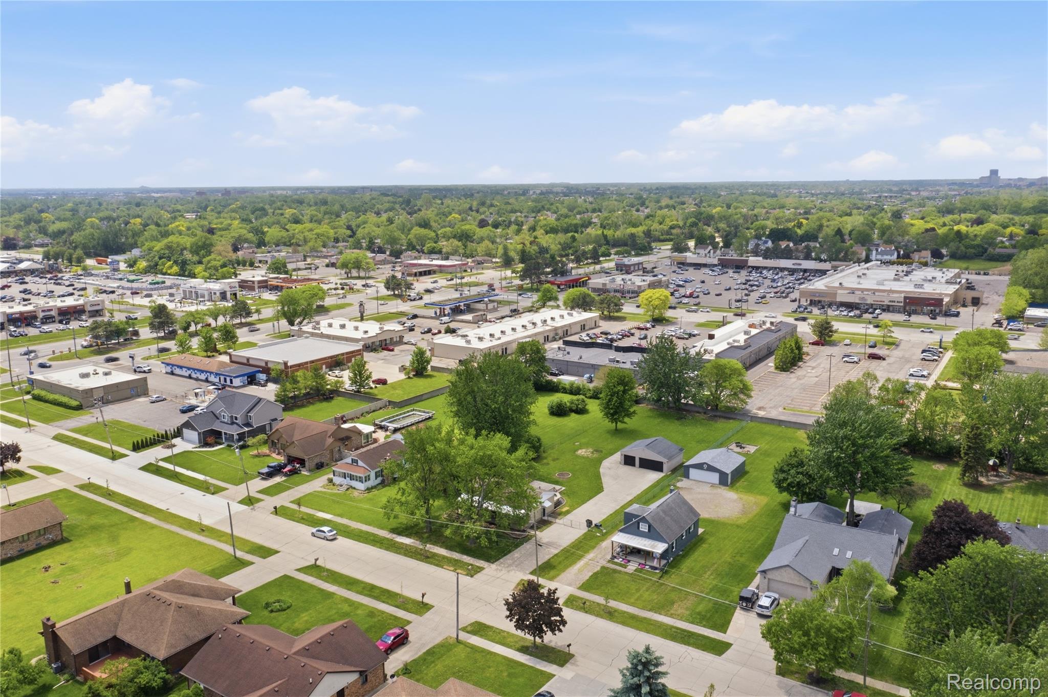 37257 Dundee Street Sterling Heights, MI 48310 - Photo 43 of 47 Aerial perspective showcasing residential properties surrounded by mature trees, with commercial developments in the background