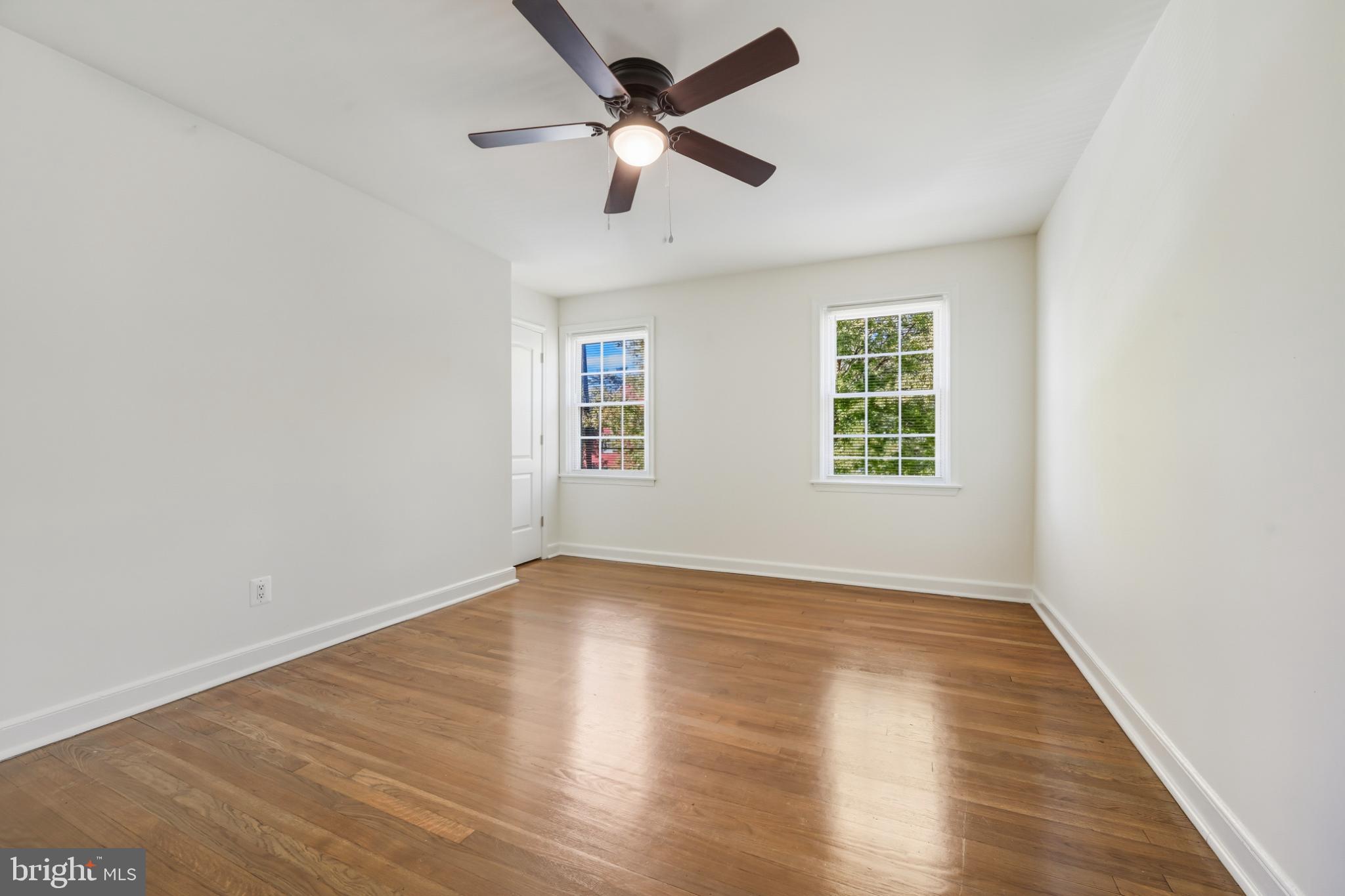 2110 Suitland Terrace Southeast Washington, DC 20020 - Photo 8 of 16 an empty room with wooden floor ceiling fan and windows