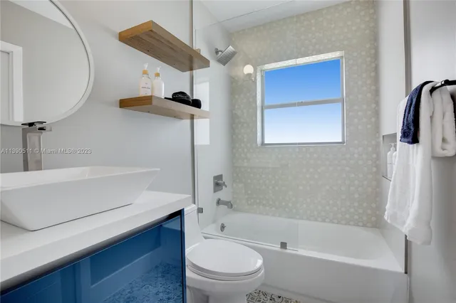 a bathroom with a bathtub shower sink vanity and toilet