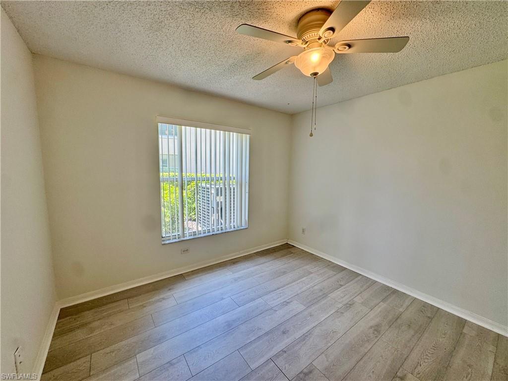 661 Squire Circle, Unit 101 Naples, FL 34104 - Photo 19 of 25 wooden floor in an empty room with a window