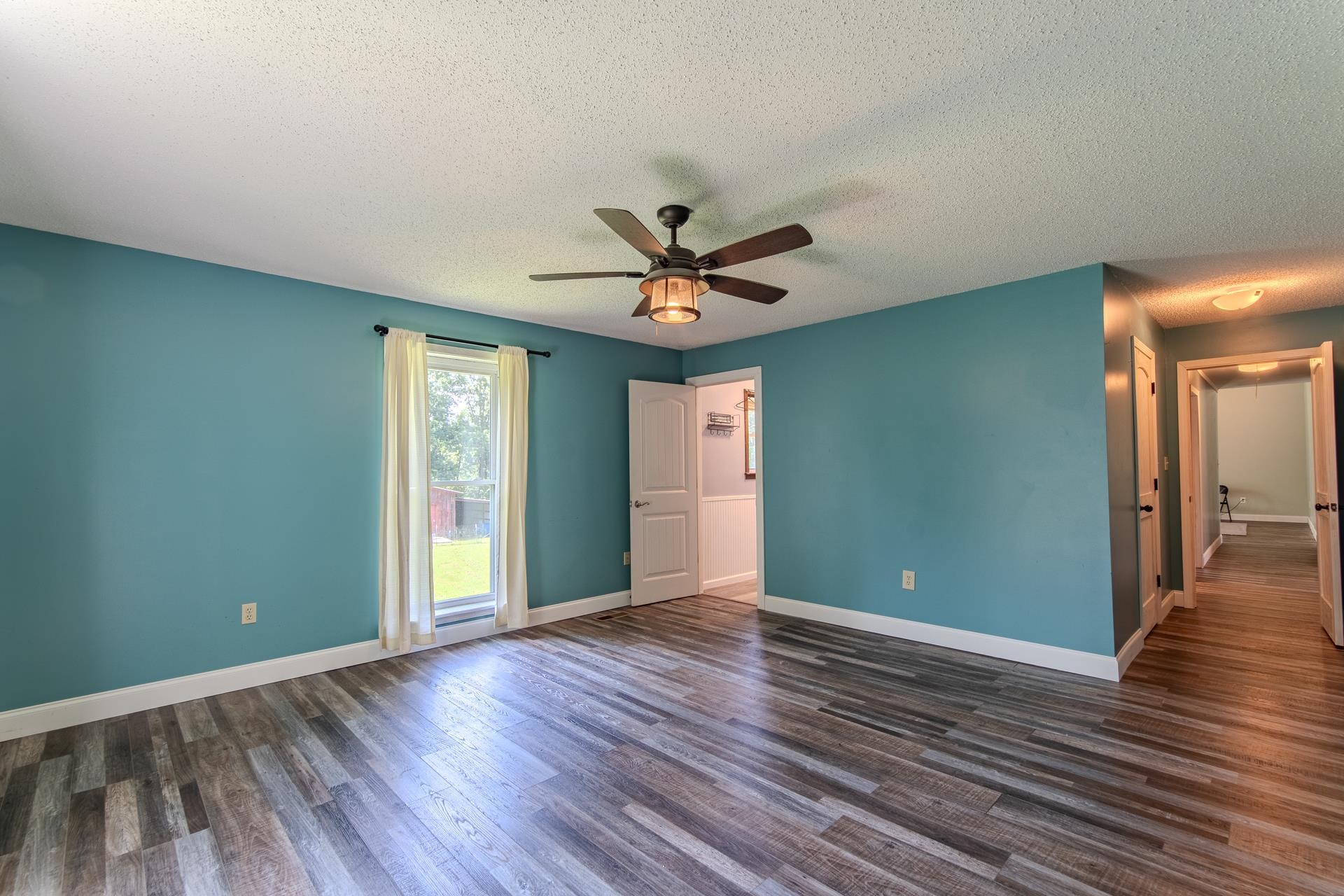 3280 Ramer Selmer Road Ramer, TN 38367 - Photo 15 of 23 an empty room with wooden floor and a ceiling fan