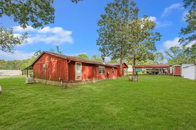 a view of a backyard with table and chairs plants and large tree