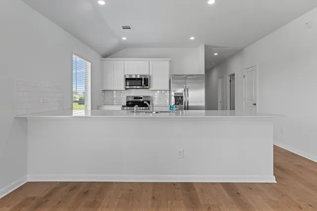 a kitchen with stainless steel appliances a refrigerator and a stove top oven
