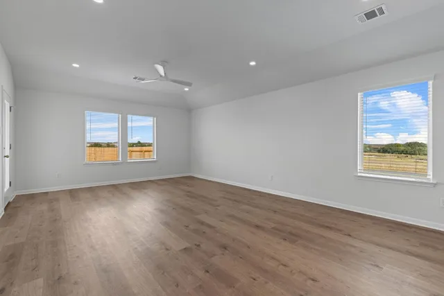an empty room with wooden floor and windows