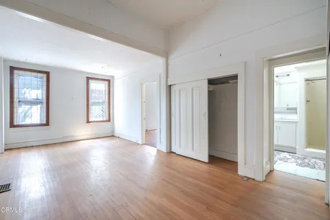an empty room with wooden floor & windows and bathroom