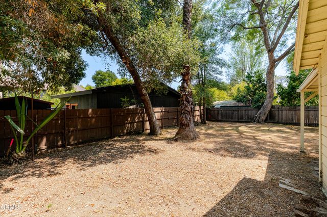 a view of a backyard with large trees and a barn