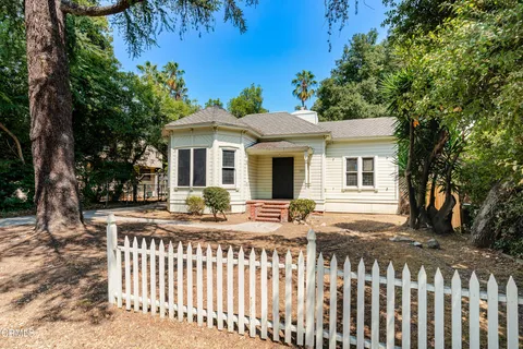 a view of a house with a small yard and wooden fence