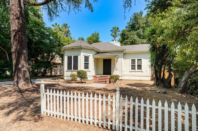a view of a house with a small yard and wooden fence