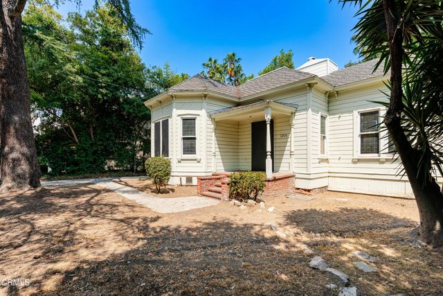 a backyard of a house with table and chairs under an umbrella
