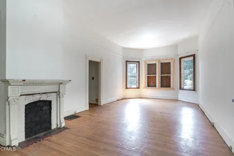 wooden floor fireplace and windows in an empty room