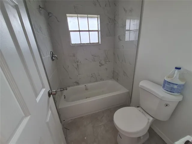 a white toilet sitting next to a bath tub