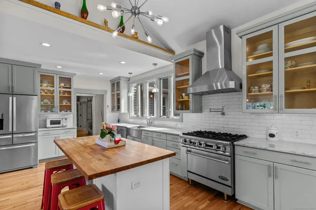 a kitchen with stainless steel appliances kitchen island a wooden floor and white cabinets