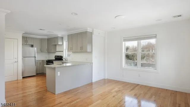 a kitchen with stainless steel appliances a white stove top oven cabinets and a wooden floor