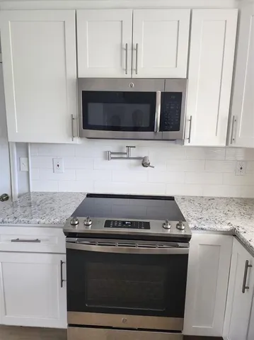a kitchen with granite countertop a stove and a microwave