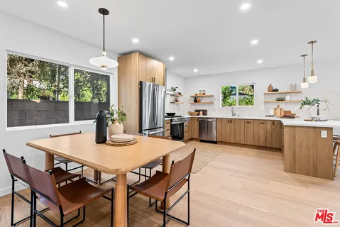 a kitchen with stainless steel appliances granite countertop a kitchen island a stove a dining table and chairs