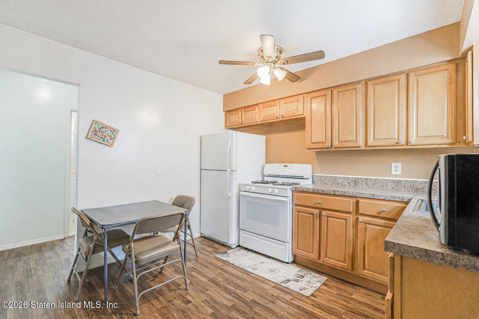 76 Berry Avenue Staten Island, NY 10312 - Photo 27 of 42 a kitchen with stainless steel appliances kitchen island a table chairs in it and wooden floors