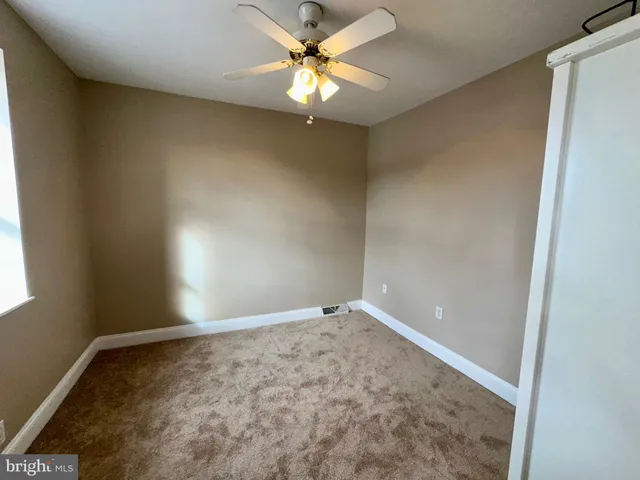 an empty room with a window and fan