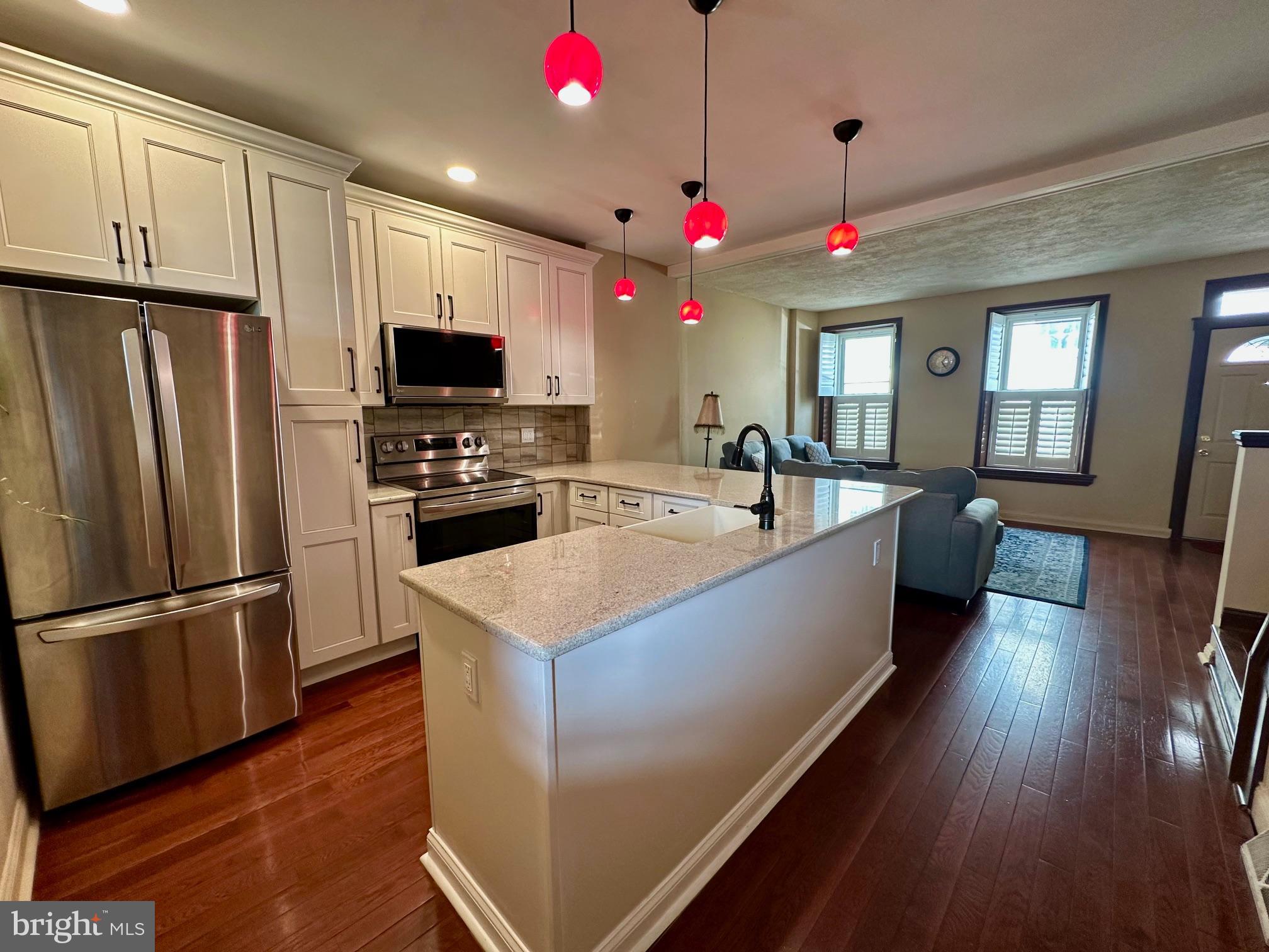 3922 Manor Street Philadelphia, PA 19128 - Photo 7 of 30 a large kitchen with granite countertop a refrigerator a oven a stove and a dining table with wooden floor