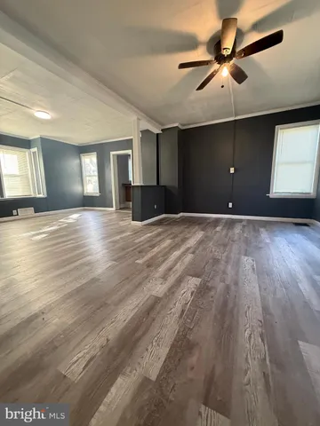 a view of an empty room with window and wooden floor