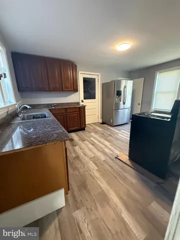 a kitchen with stainless steel appliances granite countertop a sink dishwasher stove top oven and cabinets with wooden floor