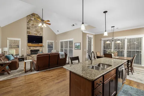 a kitchen with granite countertop a stove a kitchen island a dining table and chairs with wooden floor