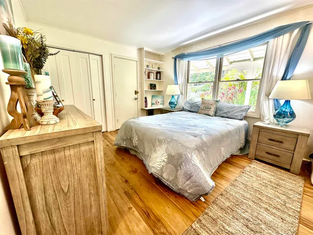 a bedroom with a bed and a dresser next to a window