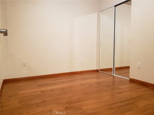 an empty room with wooden floor and fan
