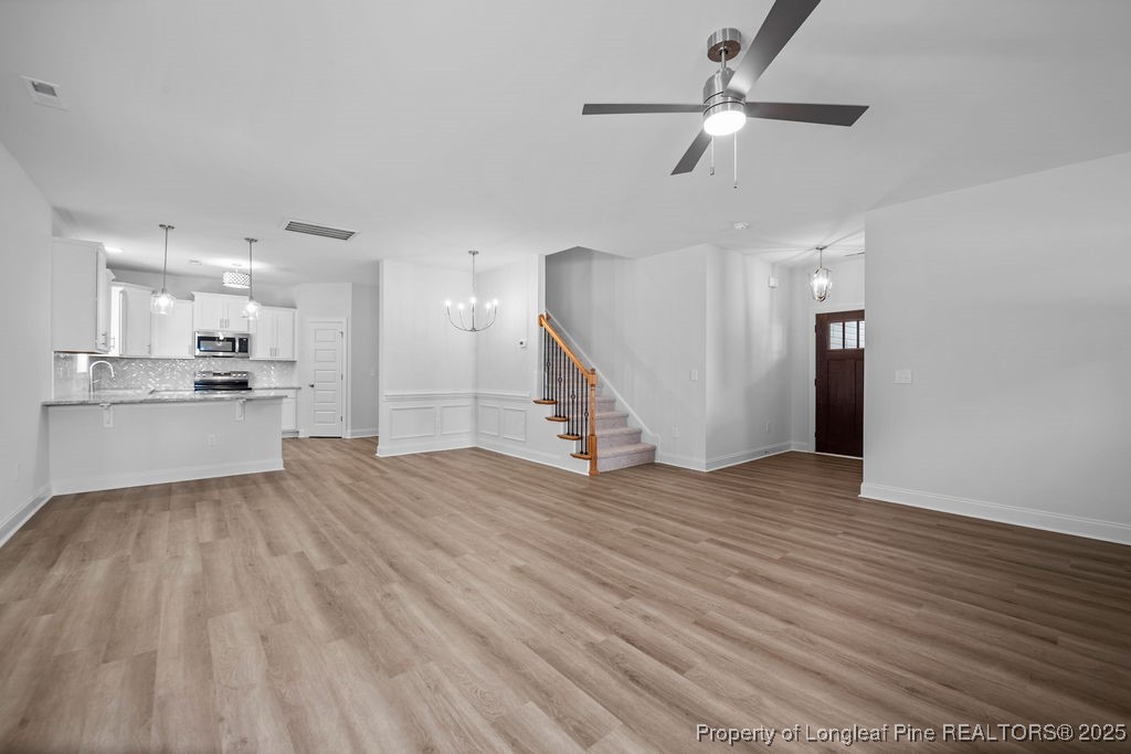 1004 Rhum Drive Fayetteville, NC 28311 - Photo 10 of 34 a view of an empty room with wooden floor a ceiling fan and kitchen view