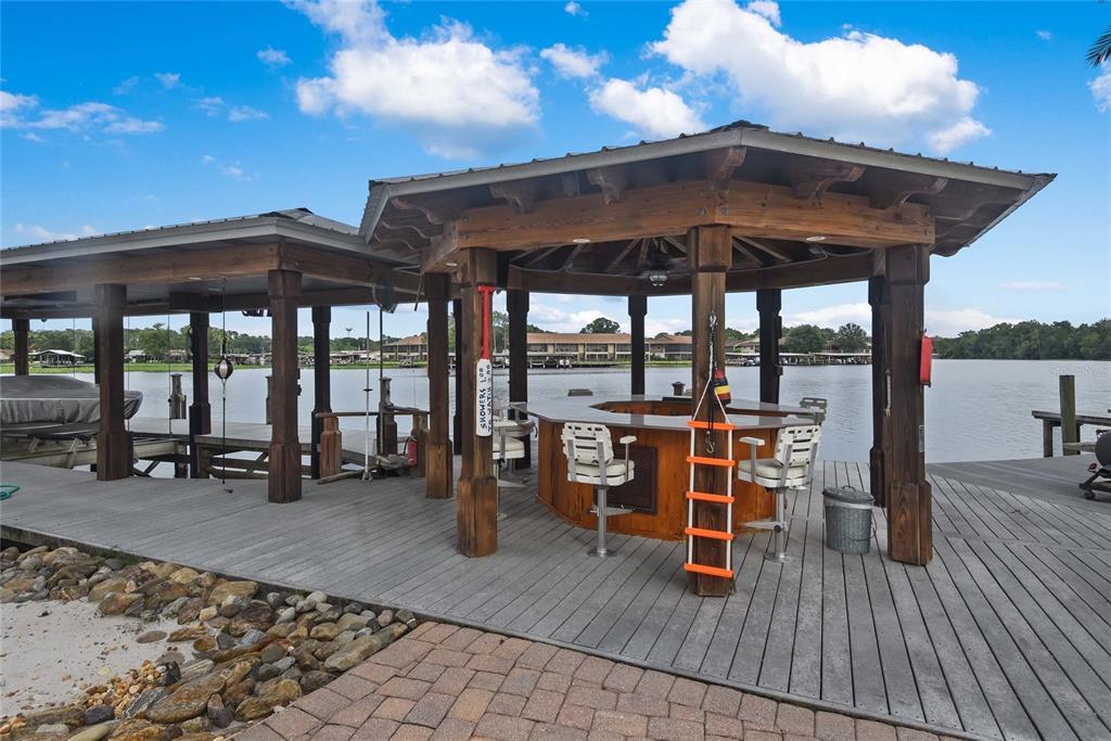 56230 Redbud Road Astor, FL 32102 - Photo 37 of 44 a view of a roof deck with table and chairs under an umbrella with wooden floor