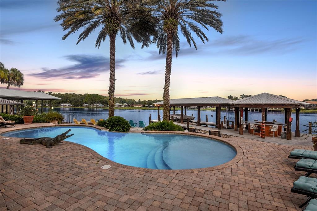 56230 Redbud Road Astor, FL 32102 - Photo 43 of 44 a view of a swimming pool with lawn chairs under an umbrella