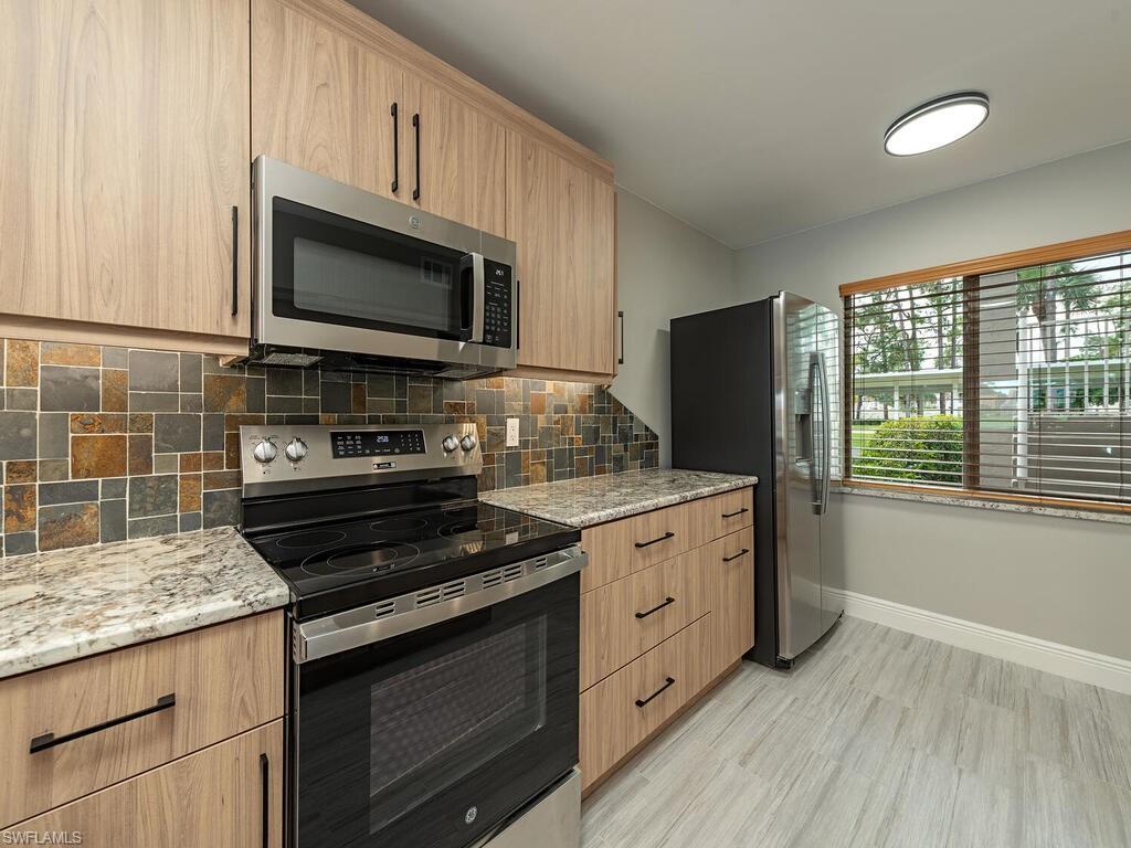 760 Augusta Boulevard, Unit D101 Naples, FL 34113 - Photo 3 of 13 a kitchen with stainless steel appliances a stove microwave and cabinets
