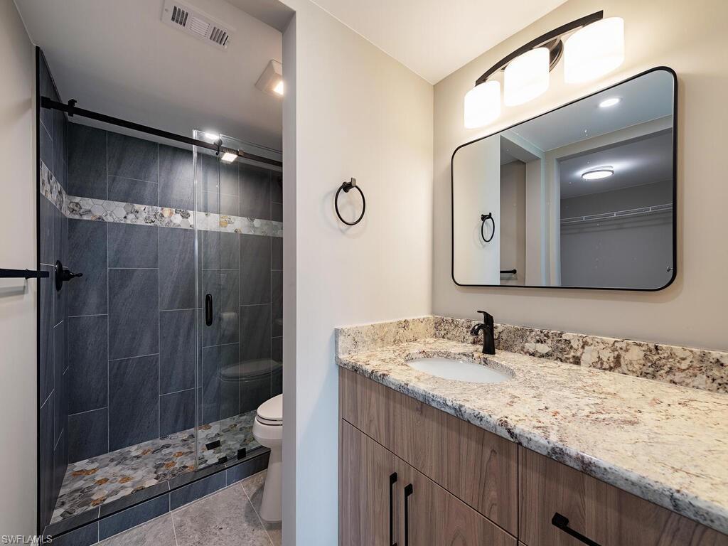760 Augusta Boulevard, Unit D101 Naples, FL 34113 - Photo 8 of 13 a bathroom with a granite countertop sink mirror and shower
