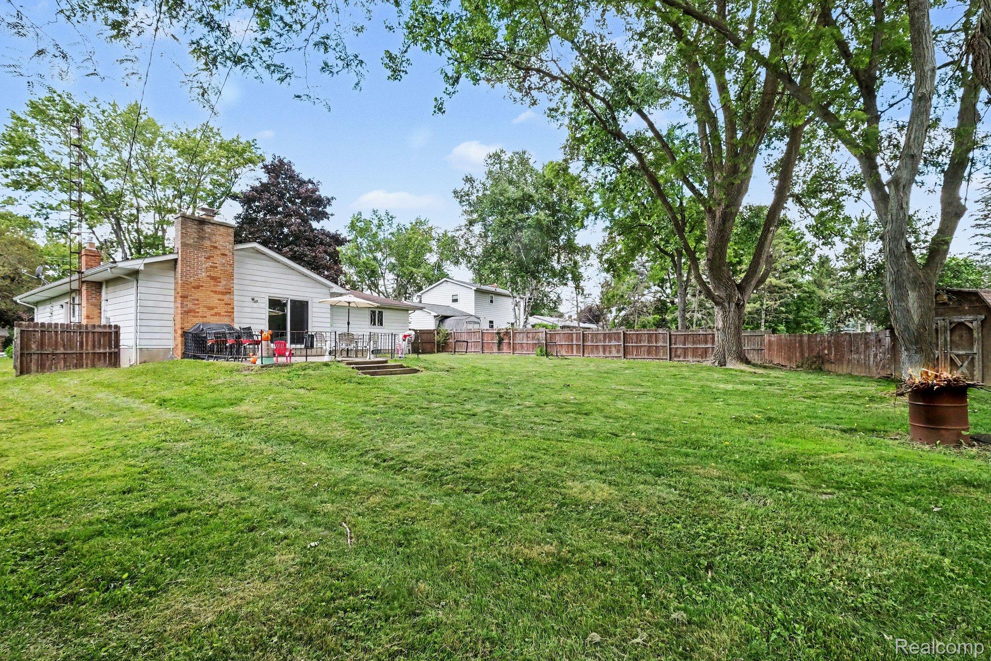 5449 South Genesee Road Grand Blanc, MI 48439 - Photo 18 of 18 Expansive backyard featuring a manicured lawn, mature trees, and a privacy fence
