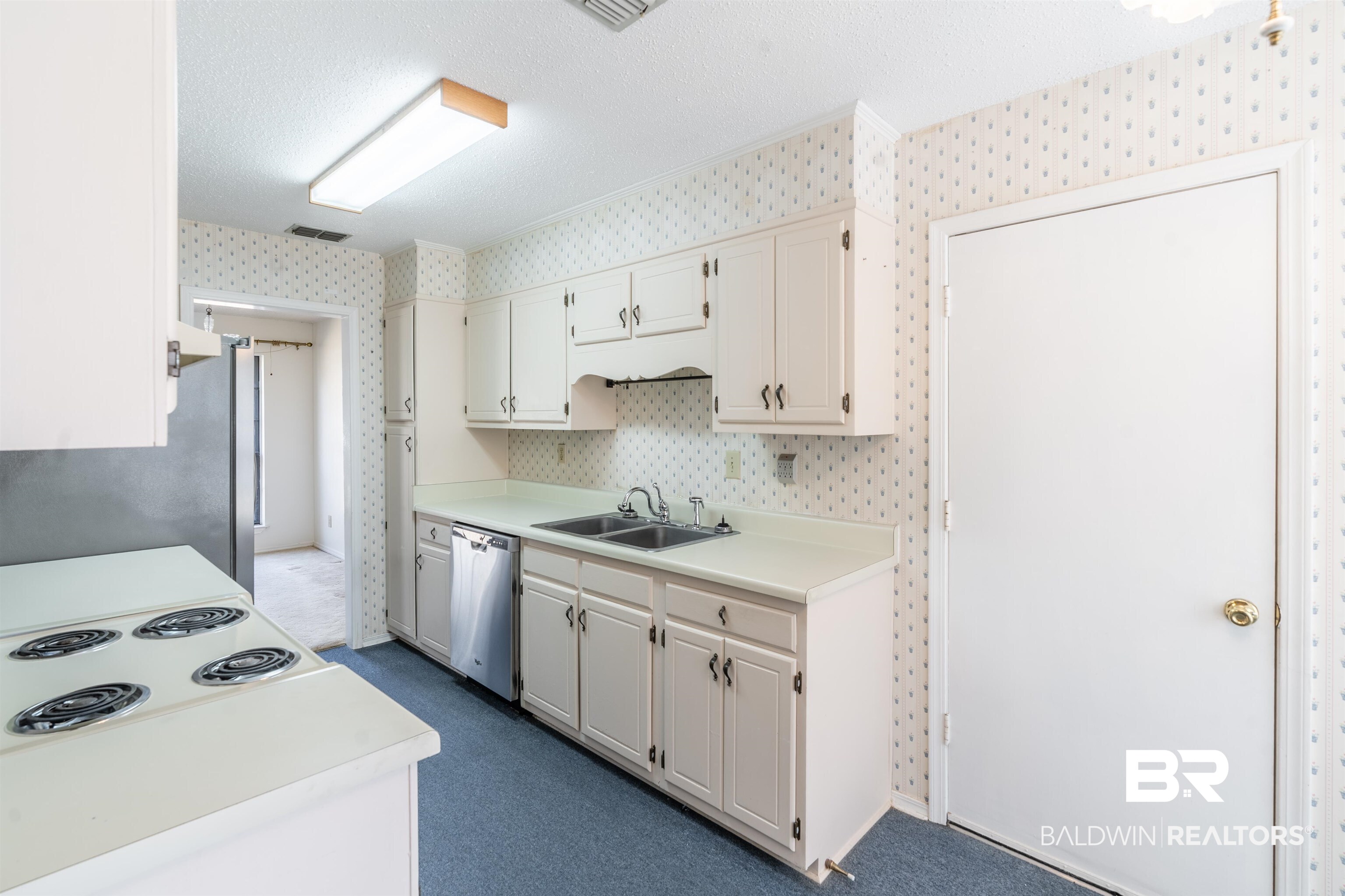 9751 Pine Knoll Road Mobile, AL 36608 - Photo 8 of 36 Kitchen with light countertops, a textured ceiling, stainless steel appliances, dark carpet, and wallpapered walls