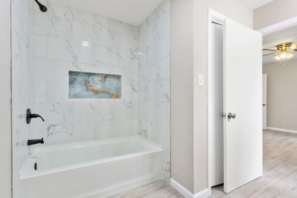 9604 Crown Ridge Road Austin, TX 78753 - Photo 15 of 24 A well-lit bathroom features a modern tub and shower with sleek, tiled walls.