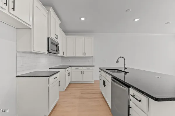 a kitchen with stainless steel appliances granite countertop white cabinets and sink